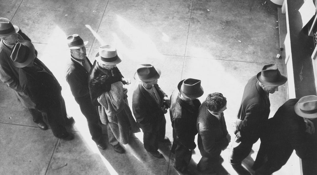 The Real Story Behind 23 of the Best Ways image (still image) Unemployment benefits aid begins. Line of men inside a division office of the State Employment Service office at San Francisco, California, waiting to register for benefits on one of the first days the office was open, (1938)